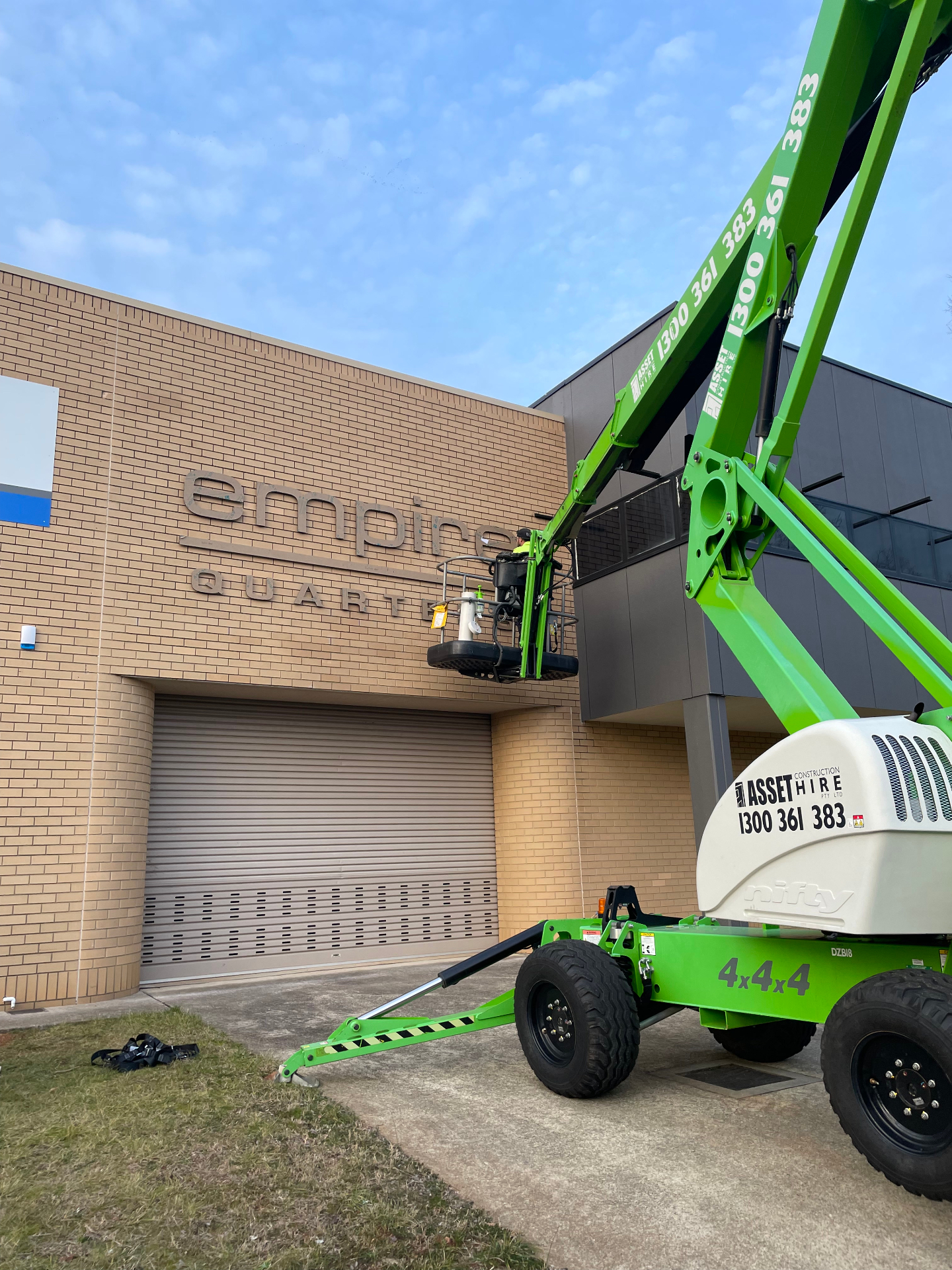 Installer on knuckle boom aligning secondary building signage