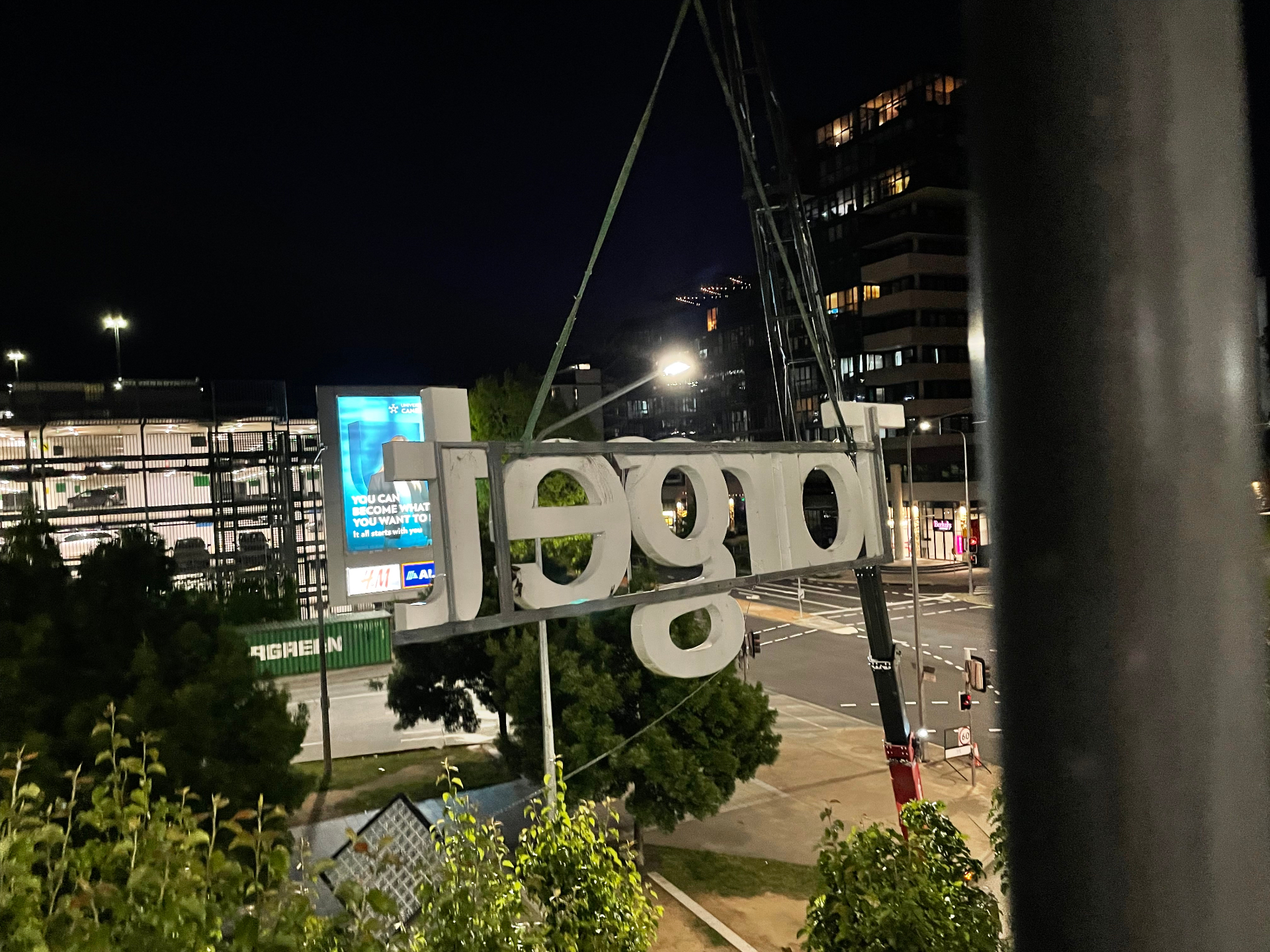 Crane lift of the 'Target' letter set clear of the facade at night